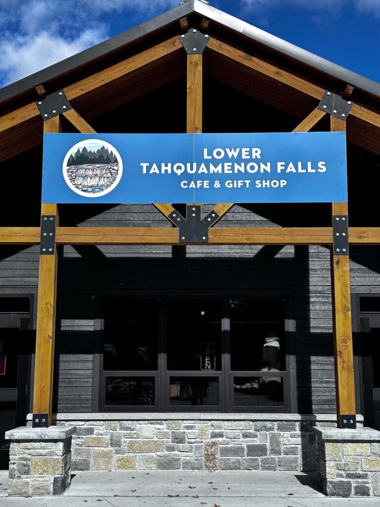 Exterior of the Lower Tahquamenon Falls Café and Gift Shop covered pavilion building with the park sign visible