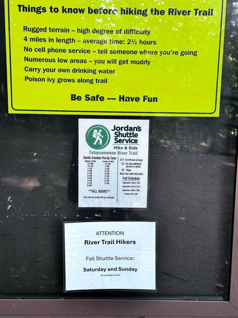 Yellow informational safety board at the Lower Tahquamenon Falls trailhead with hiking tips and trail rules for visitors