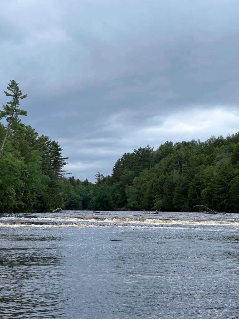 The Tahquamenon River flowing through a narrow rocky channel lined with trees at the Lower Falls area