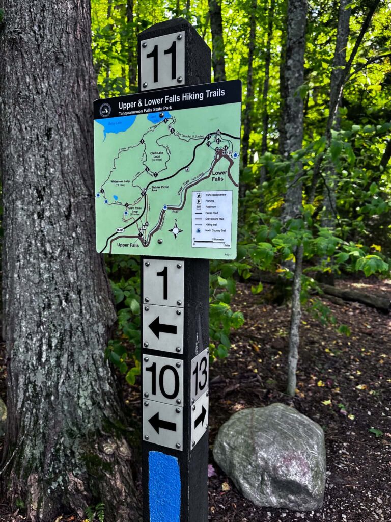 North Country Trail signpost attached to a tree near the Lower Tahquamenon Falls showing distance and trail information