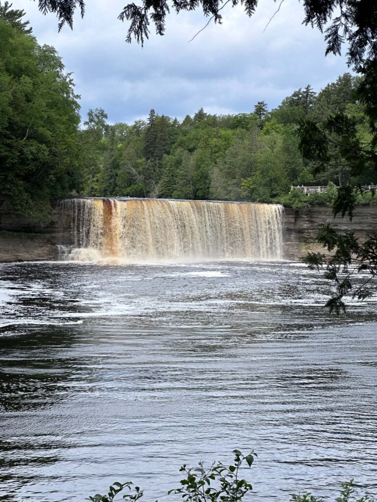 Upper Tahquamenon Falls seen from the middle of the river with surrounding pine forest