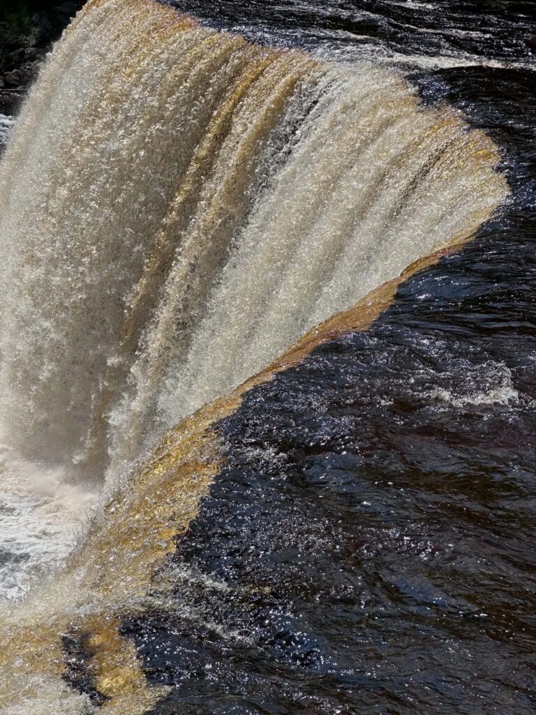 Close-up side view of Tahquamenon Falls showing amber-colored waterfall water