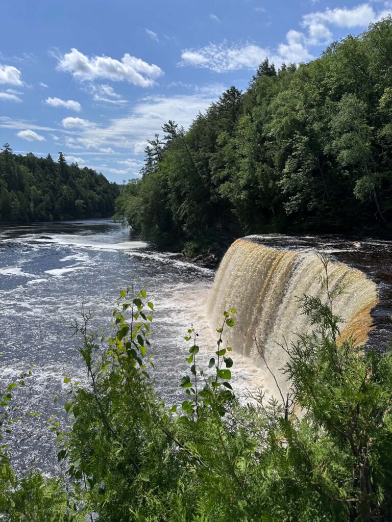 Side-angle view of Upper Tahquamenon Falls with forest-lined riverbanks