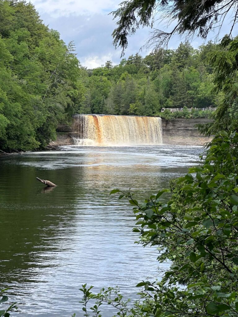 Wide view of Upper Tahquamenon Falls with calm river and forest shoreline