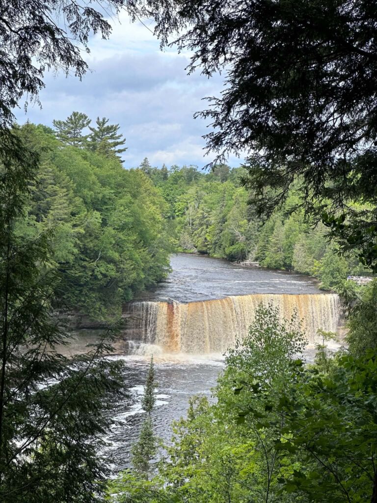 Upper Tahquamenon Falls viewed through dense green forest along the riverbank
