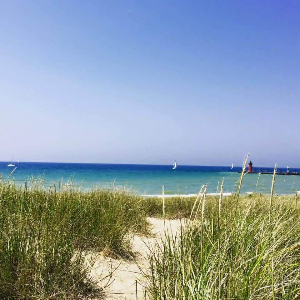 Dune grass frames the path to South Haven's beach — the red lighthouse and sailboats on Lake Michigan beyond. Photo: Mary / wanderingmichiganwisconsin.com