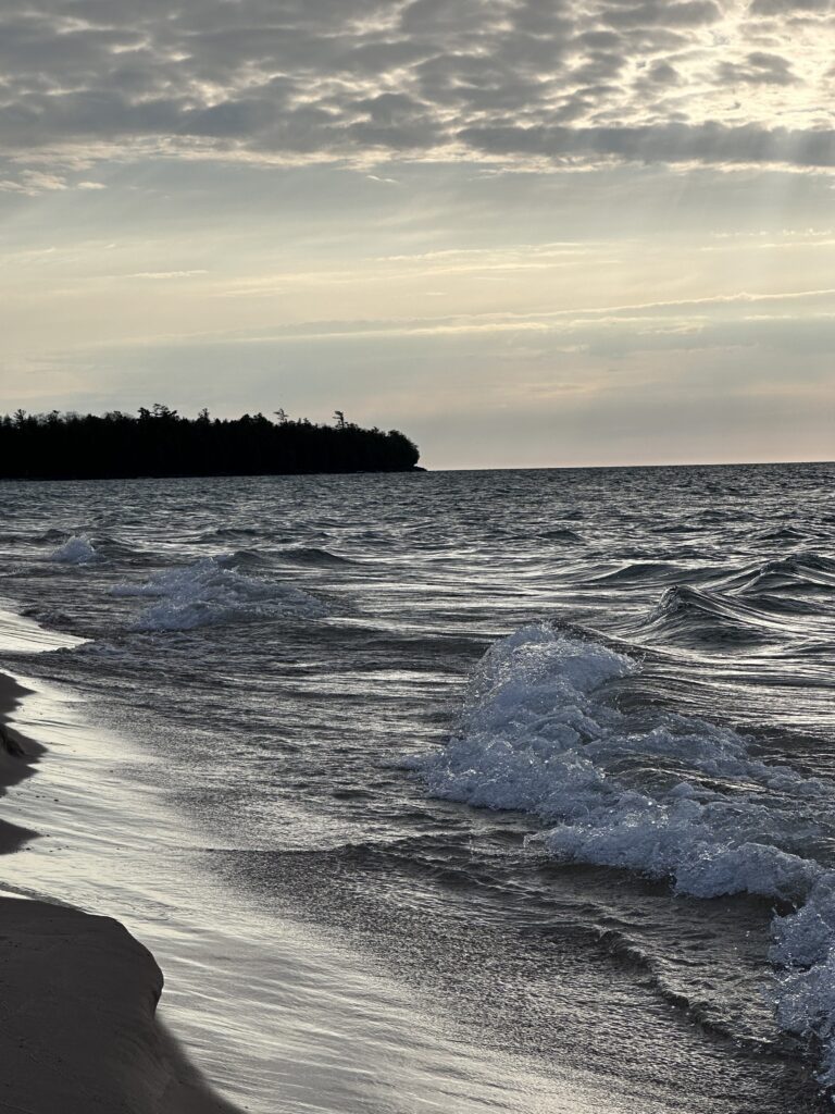 Whitefish Dunes State Park on the Lake Michigan side of Door County — the lake showing its ocean side, waves crashing on sand with the forested bluff beyond