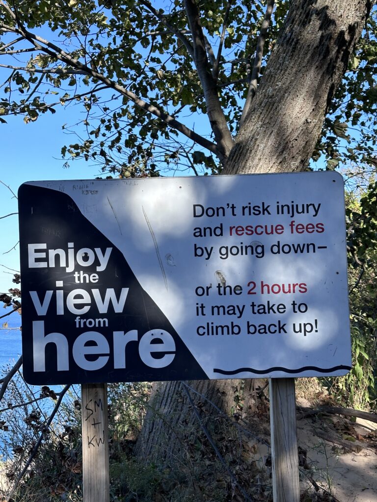 Pyramid Point warning sign at Sleeping Bear Dunes: Enjoy the view from here — Don't risk injury and rescue fees by going down — or the 2 hours it may take to climb back up.