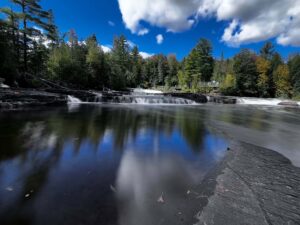 The Tahquamenon River near the Lower Falls with a dramatic storm-gray sky reflected in the calm dark water
