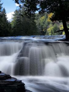 Vertical long-exposure photograph of the Lower Tahquamenon Falls with silky smooth water and a misty atmosphere rising from the cascade