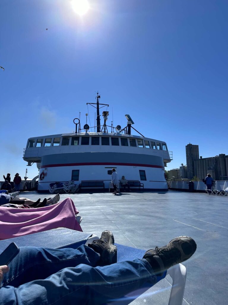 View from SS Badger lounge chair looking up at wheelhouse and upper deck passengers relaxing on Lake Michigan ferry crossing