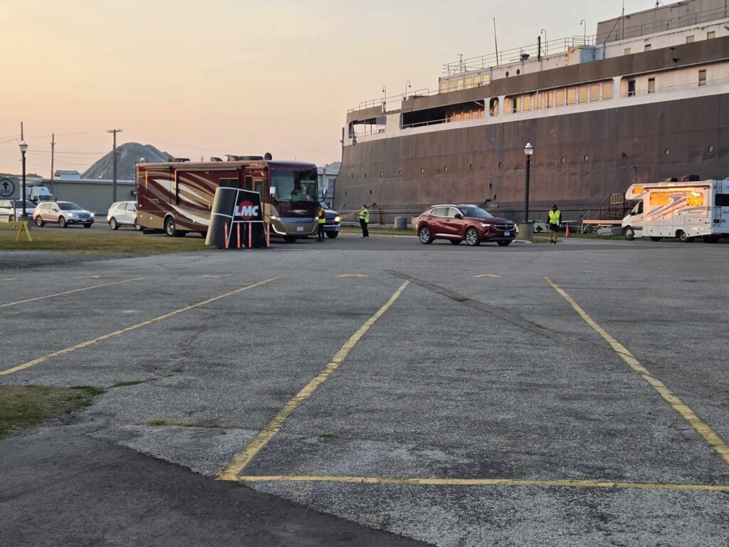 SS Badger Ludington Michigan staging lot with RV motorhome SUV and crew directing vehicles at golden hour Lake Michigan ferry