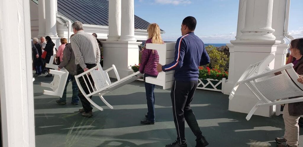 The grand hotel and their last guests bringing in the chairs from the grand porch for its seasonal closing the end of October